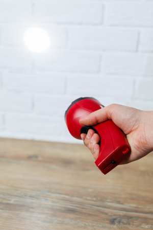 A person is firmly holding a bright red flashlight in their hand while they navigate through a dark...