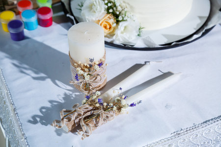 On a table positioned directly in front of a beautifully decorated cake, there are three candles flickering gentlyの写真素材