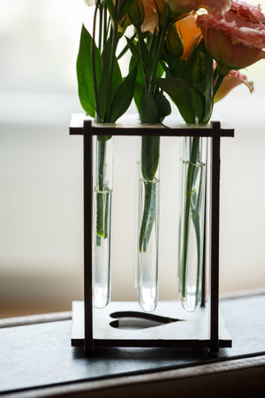 On a table, there are three test tubes that contain beautiful flowers arranged inside them, creating a lovely decorative displayの写真素材