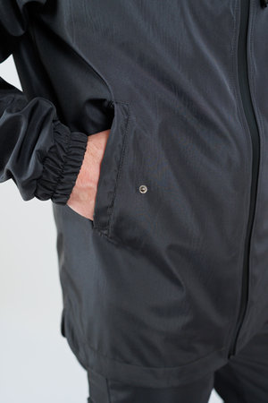 A closeup shows a sleek black athletic jacket with elastic cuffs and a side pocket for easy accessの写真素材