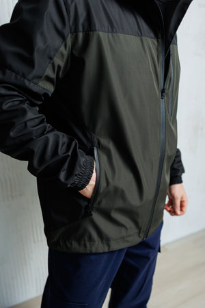 A man dressed in a stylish black and green jacket can be seen with his hand casually tucked into the pocket of his jacketの写真素材
