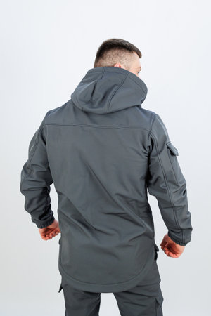 The view captures the back of a man who is wearing a stylish grey jacket that has a functional hood attached to itの写真素材