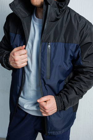 A man is seen wearing a stylish black and blue jacket that features a convenient hood, perfect for various outdoor activitiesの写真素材