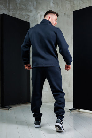The rear view of a man who is dressed in a stylish jacket paired with matching pants, showcasing a modern fashion senseの写真素材