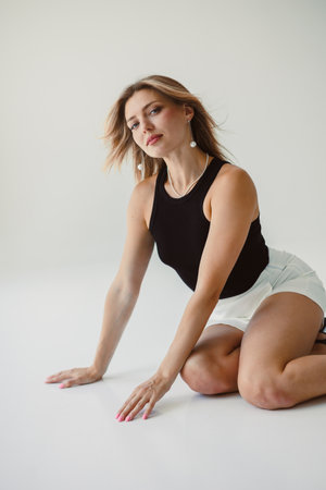 A stunning and graceful model poses elegantly against a minimalistic backdrop, showcasing chic and fashionable attire consisting of a stylish black top paired with white shortsの写真素材