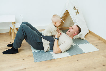 A joyful father and his young child happily play together on a cozy mat, showcasing the warmth and love of family bonding within a comfortable and inviting settingの写真素材