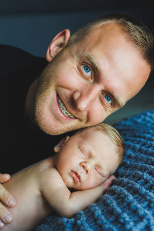 In a peaceful and warm setting, a father joyfully embraces his peacefully sleeping newborn, beautifully showcasing the profound bond of love and tenderness between them bothの写真素材