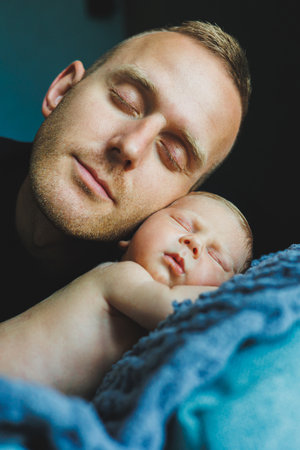 A devoted and loving father peacefully embraces his precious newborn child in a serene and soothing atmosphere, beautifully highlighting their deep bond and warm connectionの写真素材
