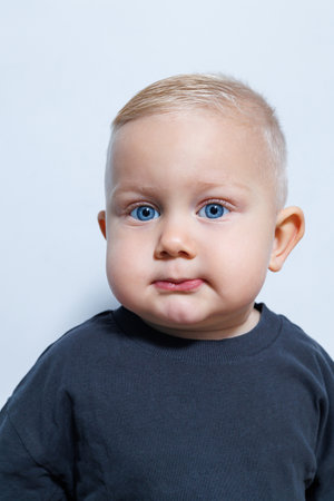 This portrait features an adorable toddler with striking blue eyes and a stylish haircut, highlighting their innocence and cuteness against a minimalist backgroundの写真素材