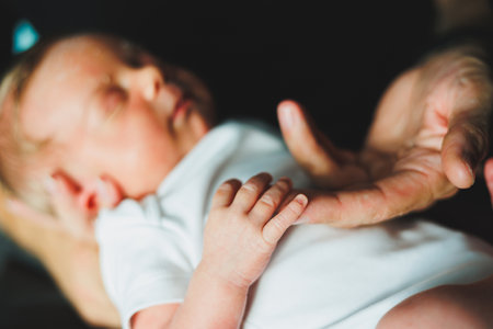 This image captures a serene moment of a loving parent cradling their sleeping newborn, illustrating the beauty of nurturing and emotional connection in early childhoodの写真素材