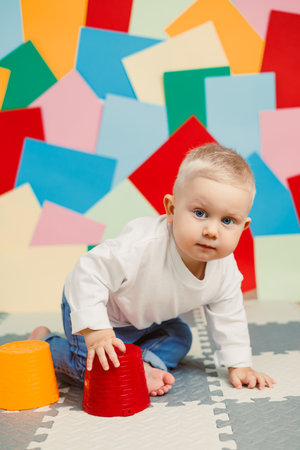 A joyful baby happily crawls on a colorful play mat that is filled with bright shapes and engaging toys, capturing a delightful moment of early childhood exploration and joyの写真素材