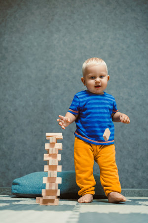 A cheerful and joyful toddler stands proudly next to a colorful and vibrant block tower, showcasing the important skills gained through imaginative play and boundless creativityの写真素材
