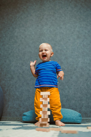 A cheerful toddler with an infectious smile stands beside a colorful block tower in a cozy room, radiating joy and inviting others to join in playful explorationの写真素材