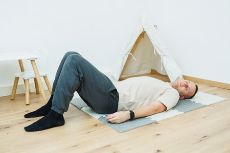 A man practices the bridge pose on a cozy mat in a warm space, promoting relaxation and wellness through mindful movement and deep breathing in his fitness journeyの写真素材