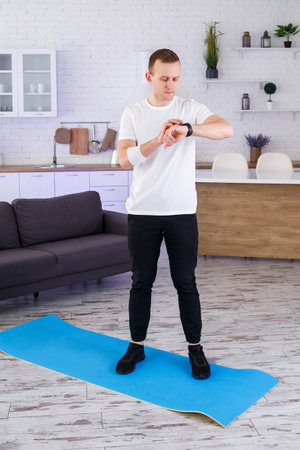 In a stylish living room, a fitness enthusiast checks their smartwatch on a yoga mat, promoting an active lifestyle that inspires others to pursue health and wellnessの写真素材