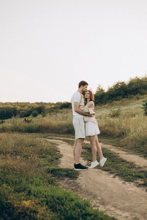 A joyful and vibrant couple sharing a tender and intimate moment in a picturesque landscape, surrounded by lush greenery and open fields, ideal for capturing love in natureの写真素材