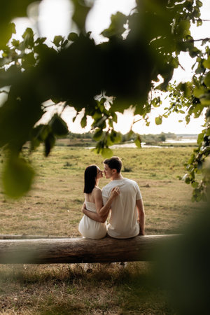 A heartfelt moment shared by a loving couple on a rustic log, surrounded by lush greenery, symbolizing their deep love and connection in a serene outdoor settingの写真素材