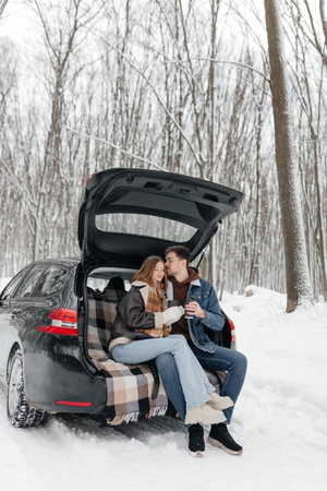 In a picturesque snowy forest, a loving couple shares warm moments inside their cozy car, parked peacefully and fully immersed in the serene beauty that winter bringsの写真素材