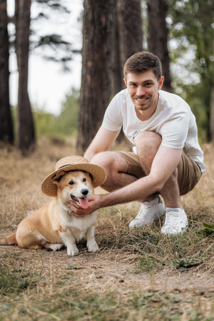 A truly joyful and delightful moment that captures a man along with his playful corgi in a stunning outdoor settingの写真素材