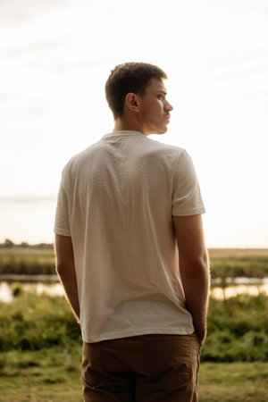 A man stands in nature, gazing at the vibrant sunset, capturing a moment of tranquility and reflectionの写真素材