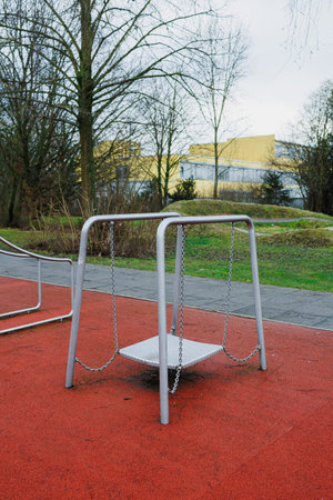 A swing set quietly sits on a vibrant red surfaceの写真素材