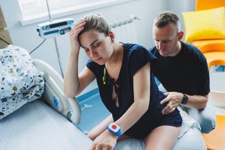 Pregnant woman feels severe pain during childbirth in hospital ward. Caring man helps woman during childbirth and massages her back. Support and love concept.の写真素材