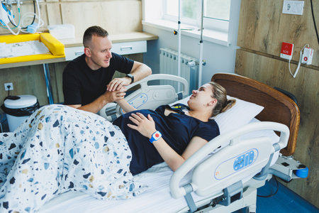 Woman lying feeling pain during childbirth. Pregnancy, childbirth concept. Caring man holding pregnant wife's hand during childbirth. Supportive man helping young woman during childbirth.の写真素材