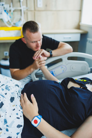 Caring husband holding pregnant wife's hand during childbirth. Supporting husband helping young woman during childbirth. Concept of support and medical care during childbirth.の写真素材