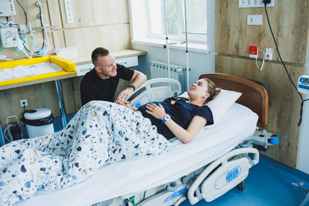 Woman lying feeling pain during childbirth. Pregnancy, childbirth concept. Caring man holding pregnant wife's hand during childbirth. Supportive man helping young woman during childbirth.の写真素材