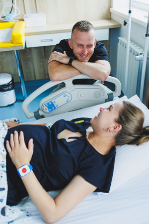 Woman lying feeling pain during childbirth. Pregnancy, childbirth concept. Caring man holding pregnant wife's hand during childbirth. Supportive man helping young woman during childbirth.の写真素材