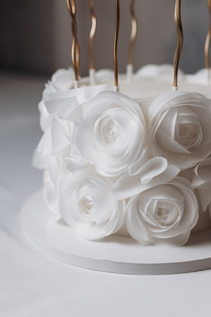 This stunning white cake, decorated with sugar roses and golden candles, is perfect for weddings, anniversaries, or any special celebration, embodying elegance and charmの写真素材