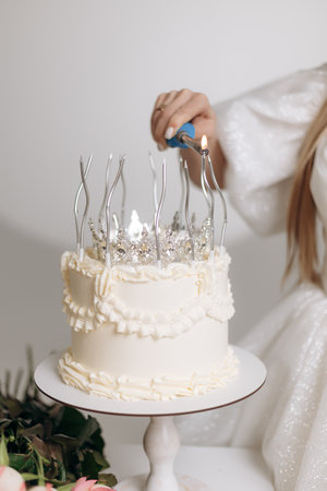 A beautifully decorated white cake with silver crown candle holders is lit, becoming a stunning centerpiece for birthdays or anniversaries, adding luxury and joy to the eventの写真素材