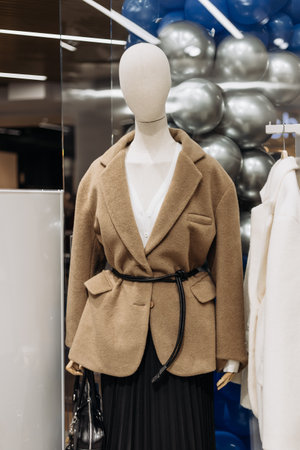 The stylish brown wool blazer with a belted waist is displayed on a mannequin in a boutique, perfect for trendy, sophisticated autumn looks to elevate any wardrobeの写真素材