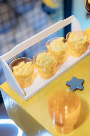 Bright yellow candies in transparent cups on a vibrant yellow surface create an eyecatching display perfect for parties and special events, ensuring a delightful atmosphereの写真素材