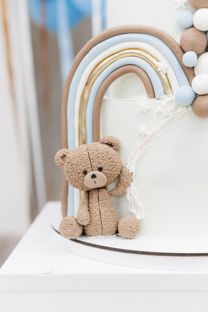 Delightful cake featuring a charming teddy bear and vibrant rainbow decorations, ideal for birthday parties or baby showers. Sweet and playful design for cake lovers.の写真素材