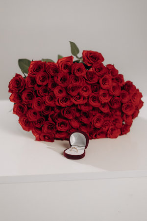 A stunning array of vibrant red roses alongside an elegantly opened velvet engagement ring box creates the ideal and romantic setting for a proposal that will be cherished foreverの写真素材