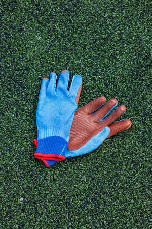 A vivid and vibrant pair of multicolored work gloves is neatly laid out against a backdrop of synthetic grass, making them perfect for gardening or other outdoor activitiesの写真素材