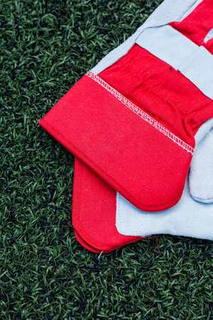 This image showcases striking red and grey sports gloves on vibrant green artificial grass, perfect...