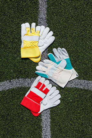 A vibrant collection of assorted gloves displayed on a green grass surface, showcasing different styles and colors perfect for sports and outdoor activitiesの写真素材