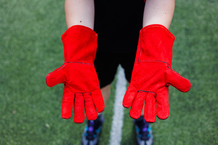 A person in bright red gloves stands out on lush green turf.の写真素材
