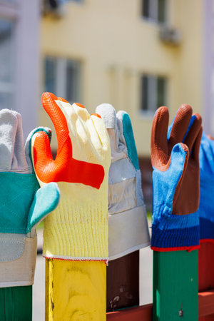 A vibrant assortment of gardening and work gloves displayed on a fence, showcasing different styles...