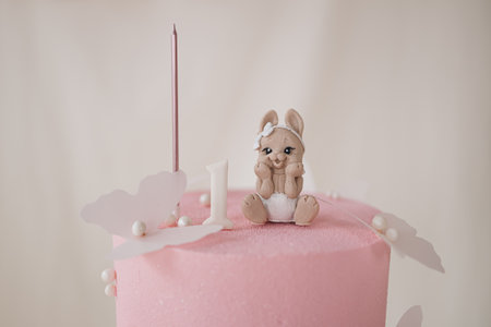 A delightful pink birthday cake adorned with a charming bunny figurine, ideal for celebrating a childs very first birthday in an elegant and sweet manner filled with joy and funの写真素材