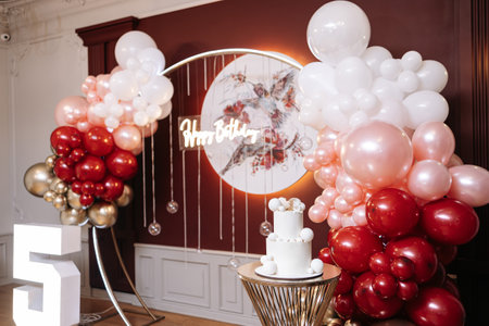 A beautifully arranged 5th birthday celebration featuring elegant balloon decorations, a delicious cake, and artistic floral dcorの写真素材