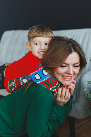 A loving mother shares joyful moments filled with laughter with her young son indoors, highlighting their unique bond and the essence of parenting and childhoodの写真素材