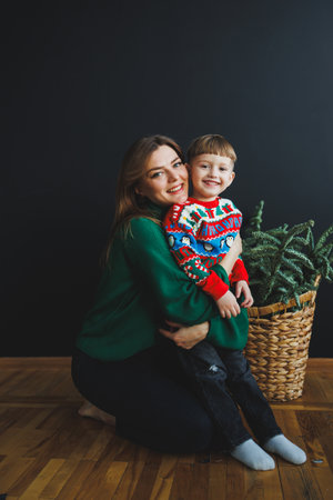 A loving and caring mother along with her young son, both filled with joy and dressed in festive attire, beautifully radiate warmth and affection even against a dark backdropの写真素材
