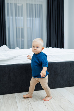 In a beautifully designed modern bedroom, a charming toddler takes wobbly steps, embodying the joy of early childhood exploration in a lovely contemporary settingの写真素材