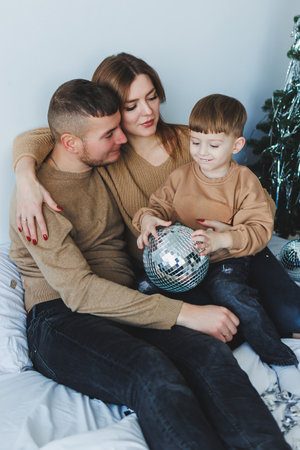 A heartfelt family moment sees a joyful child holding a shiny disco ball that sparkles brightly, radiating love and togetherness during this unifying holiday seasonの写真素材