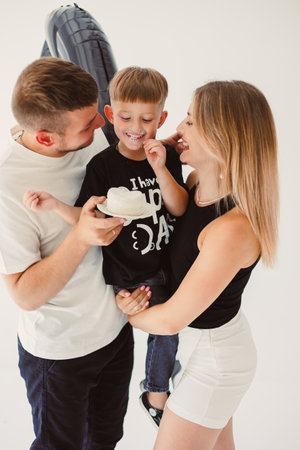 This scene shows a loving family joyfully spending time together, with a child embraced by caring parents in a modern studio, highlighting their warm, affectionate bondの写真素材