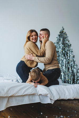 A joyful family enjoys playful moments on a comfy bed, surrounded by colorful decorations, capturing the warmth of togetherness in a cozy atmosphere full of loveの写真素材