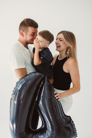 A joyful family portrait of a smiling couple and their young boy, captured in a loving studio setting, perfect for lifestyle imagery of happiness and togethernessの写真素材